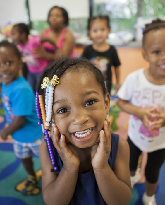 At daycare, a group of African American young girls smile at the camera