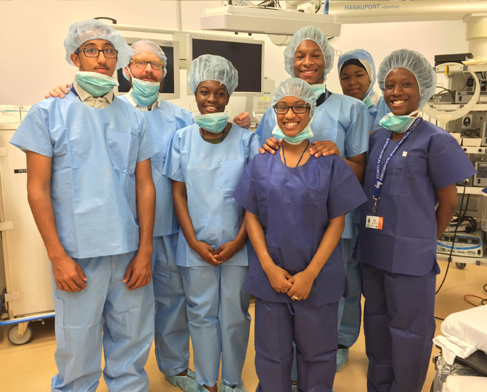 Group of student interns wearing scrubs pose with mentor
